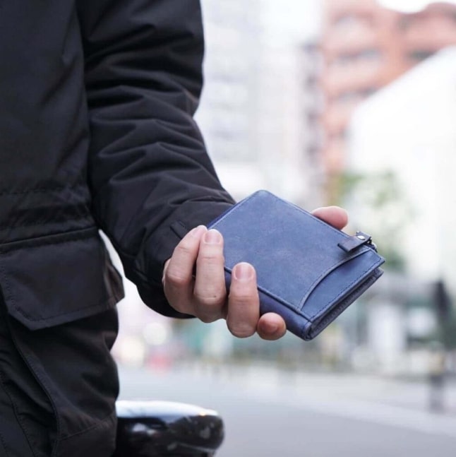 ハレルヤの二つ折りミニ財布を片手に持つ男性