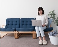 ソファーに座ってノートパソコンを操作する女性
