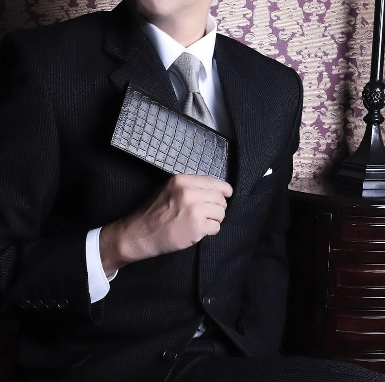 メゾンドヒロアンのクロコダイル長財布を持つ男性